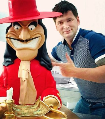 Man posing with a large cartoon pirate statue.