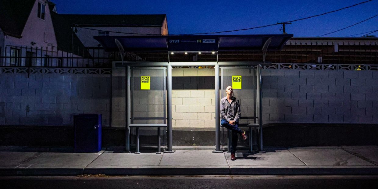 Man sitting alone at a bus stop at night.