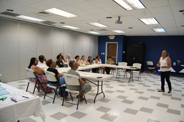Woman presenting to a seated group in a classroom.
