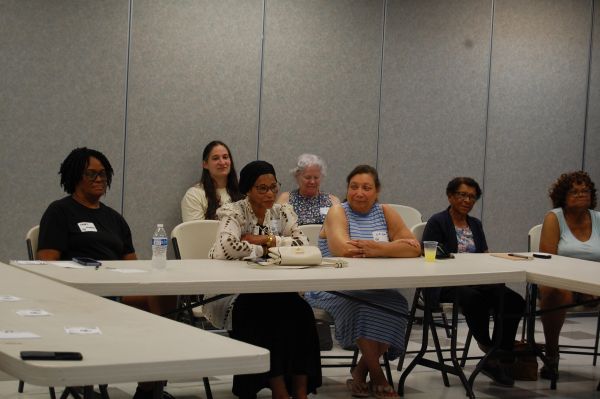 Group of women seated around tables in a meeting room.