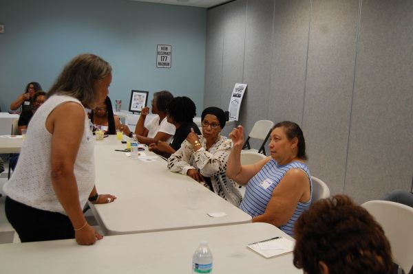 Women engaged in a discussion around a table in a meeting room.