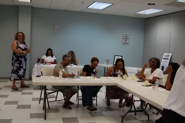 Women seated around tables in a meeting room.