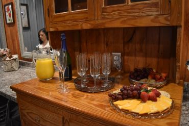 Cheese platter with fruits and drinks on a wooden sideboard.