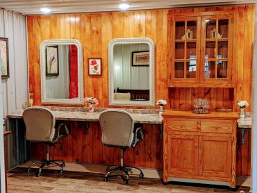Cozy wooden vanity area with two chairs and mirrors.