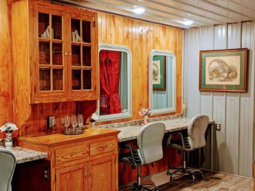 Cozy wooden vanity area with mirrors and chairs.
