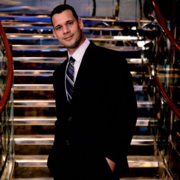 Man in a suit smiling on stairs.