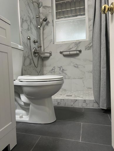 Modern bathroom with white toilet and marble-patterned shower area.