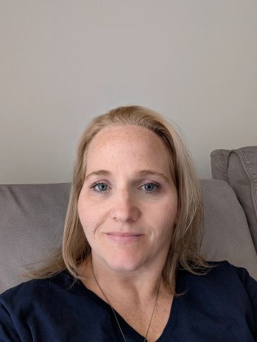 Woman with blonde hair sitting on a couch.