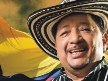 Hombre sonriente con sombrero tradicional y bandera de Colombia.