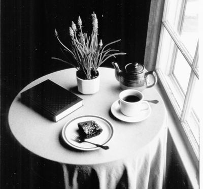A cozy table setup with tea, a book, and a snack near a window.