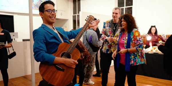 Man joyfully playing guitar at a lively indoor social event.