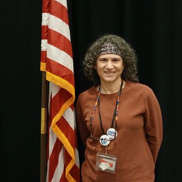 Woman standing next to an American flag with a smile.