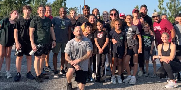 A diverse group of people posing together outdoors on a sunny day.