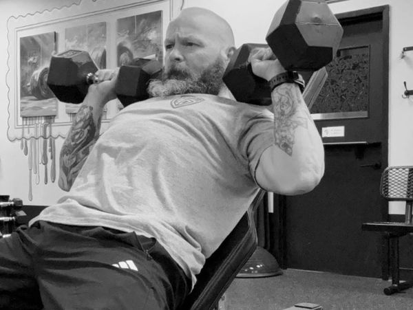 Man lifting dumbbells on an incline bench at the gym.