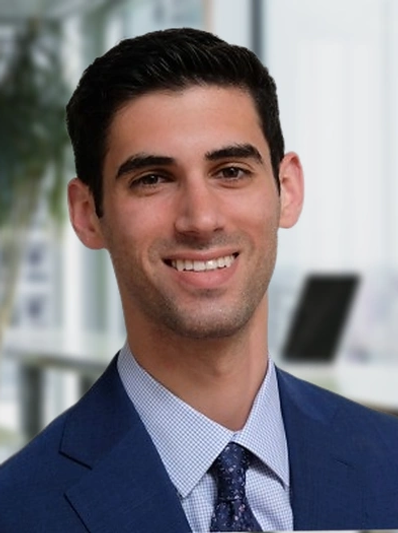 Smiling man in a blue suit and patterned tie.