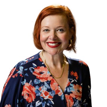 Smiling woman with red hair and floral dress.