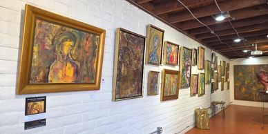 Gallery wall showcasing various framed abstract paintings in warm tones.