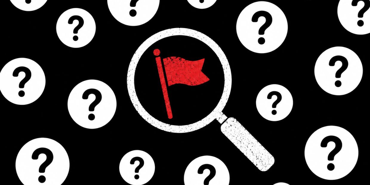 Magnifying glass highlights a red flag among question marks.