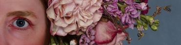 Close-up of a person's eye next to a cluster of soft pink and purple flowers.
