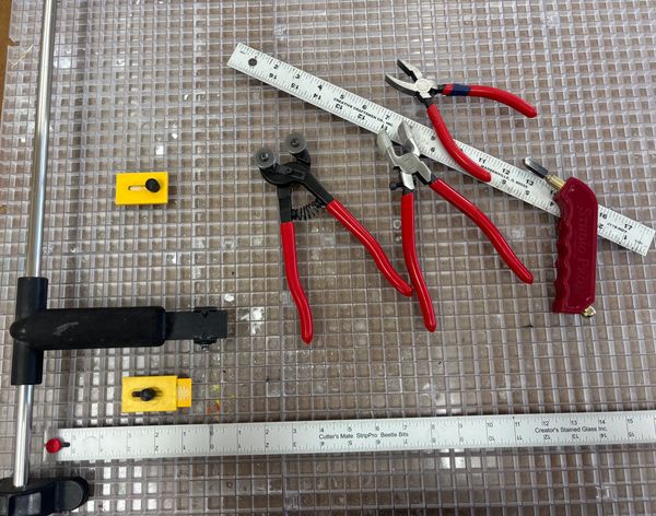 A collection of cutting and measuring hand tools on a grid surface.