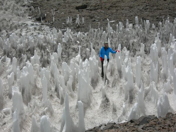 Person exploring tall ice pinnacles in a rugged snowy landscape.