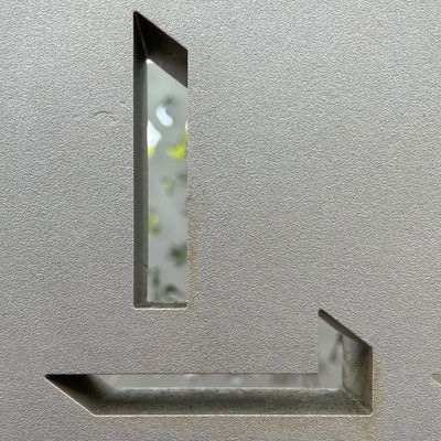 Close-up of a textured surface with rectangular cutouts revealing blurred background.