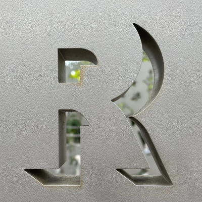 Close-up of a textured surface with a cutout letter R revealing a blurred background.