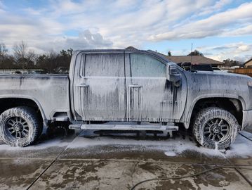 Truck covered in soap foam during a wash.