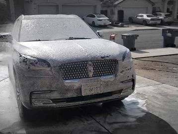 Luxury SUV covered in soap foam during a wash.