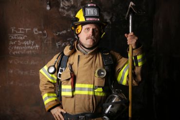 Firefighter in full gear holding a tool.