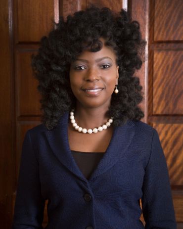 Professional woman smiling with pearl necklace and earrings.