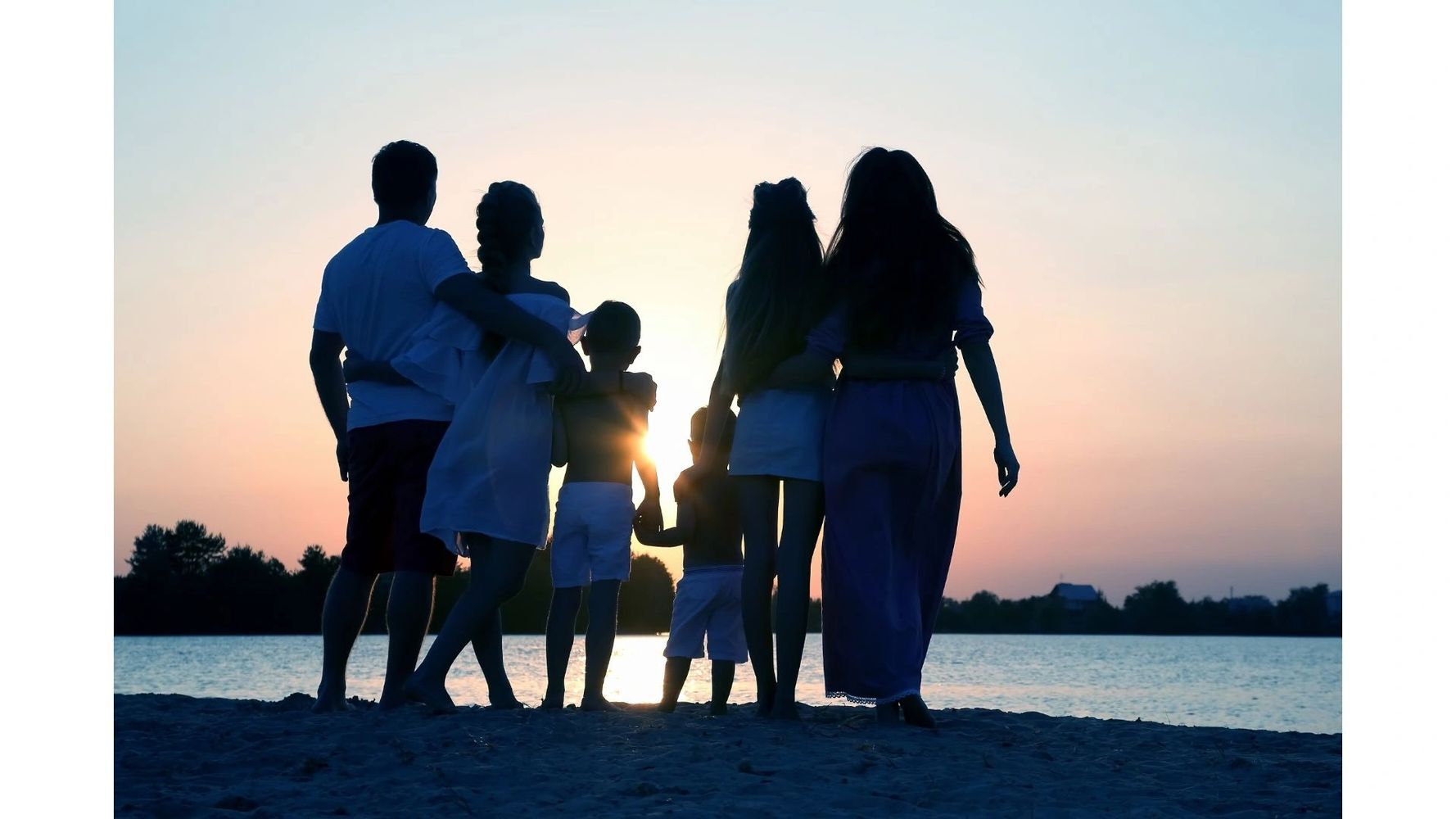 Family of six standing close together looking at a sunset