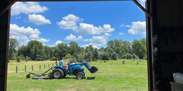 Son mowing the farm on a beautiful, blue sky, Summer day. Photo from inside the barn looking out.