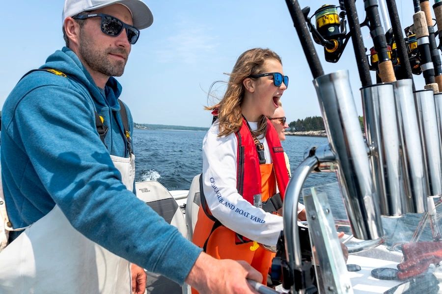 Captain Joe Jerome teaching a teenage girl how to drive a boat in Maine