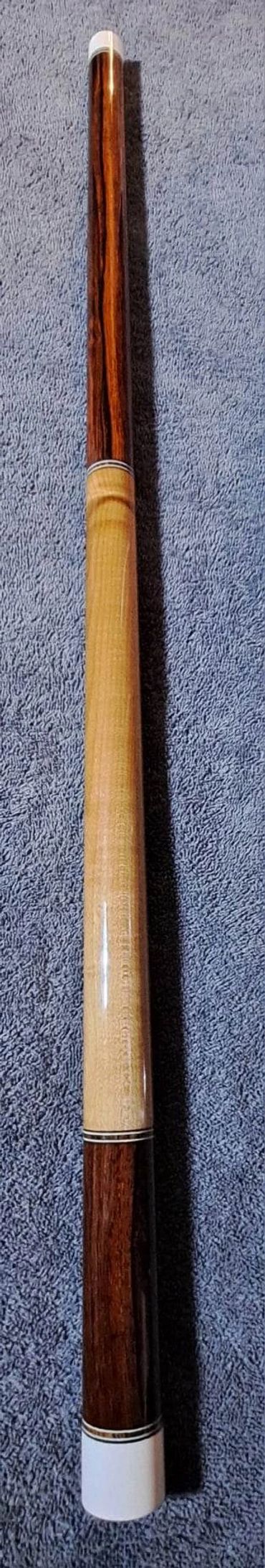 Wooden cue stick on a textured surface.