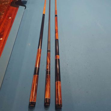 Three billiard cues placed on a pool table.