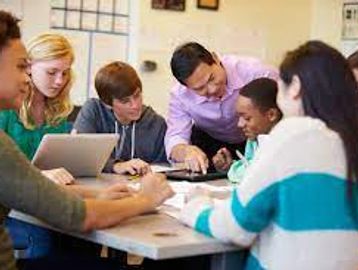 A teacher helps students with a group project in a classroom.