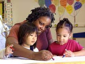 Teacher helping two young children with their drawing activity.