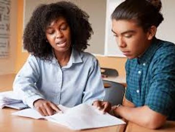 A tutor helping a student with his studies at a desk.