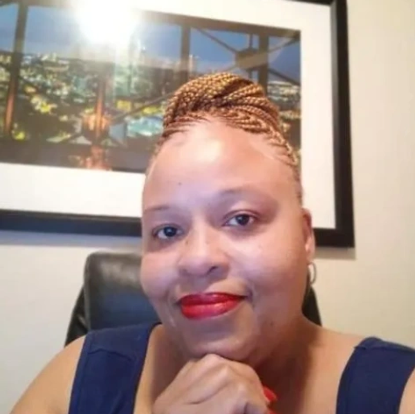 Woman smiling with braided hair and red lipstick.