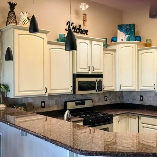 Clean kitchen with white cabinets and a brown granite countertop.
