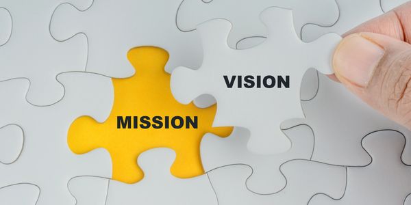A puzzle piece labeled 'VISION' fitting into a space labeled 'MISSION'.