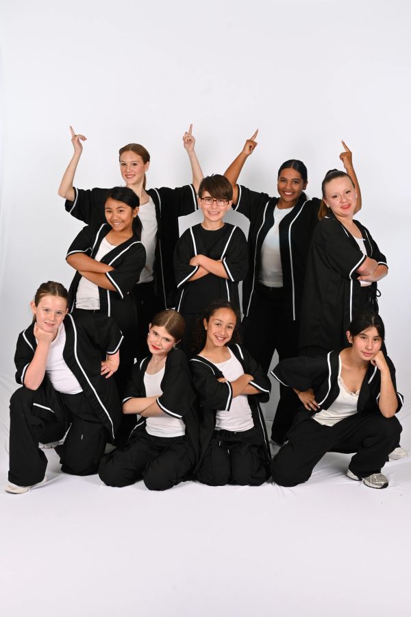 A group of young dancers in coordinated black and white outfits posing confidently.