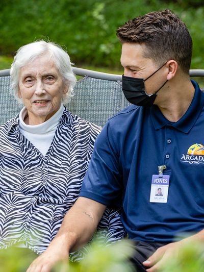 Resident and Caregiver Sitting Together Outside on a Swing