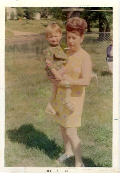 An old picture of an old lady holding a blonde child in a field