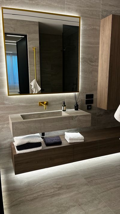 Ванна кімната з дерев'яними меблями та золотистою сантехнікою, дзеркало з підсвічуванням