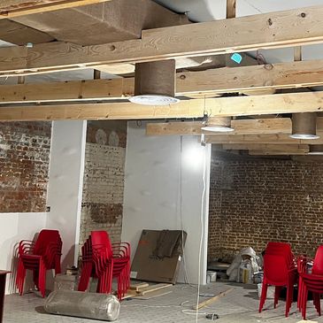 Реконструкція інтер'єру ресторану з дерев'яними балками, червоними стільцями та цегляними стінами