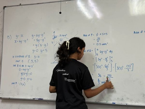 DDEC Student Madhiha doing an integration question on A Maths and explaining to her fellow classmate