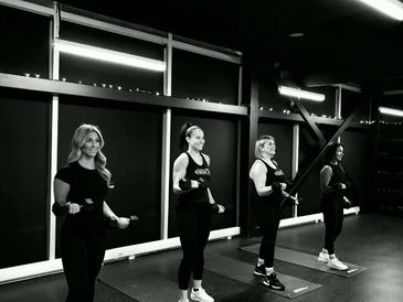 Four women exercising with dumbbells in a gym.