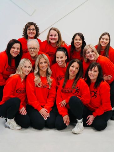 Group of women in matching red sweatshirts posing together and smiling.